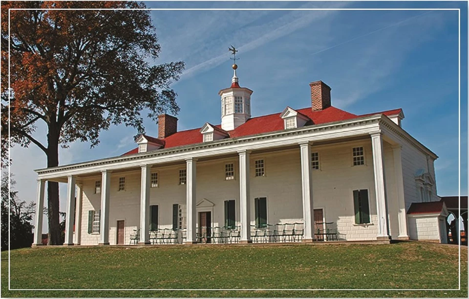 An old colonial-style house with a red roof and white columns under a blue sky